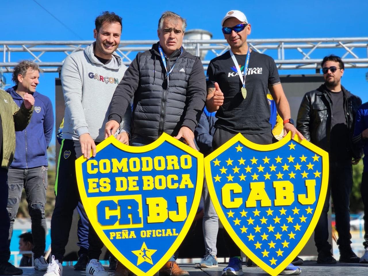 Organizadores en el escenario con los escudos de la peña y de Boca
